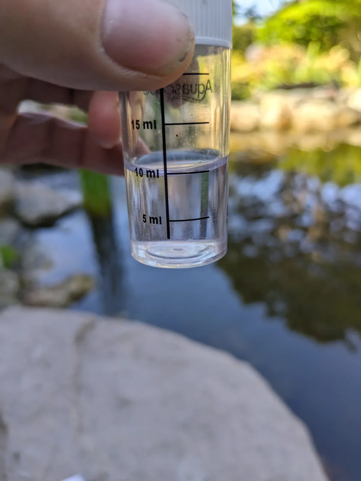Water quality sample being checked beside a clear pond