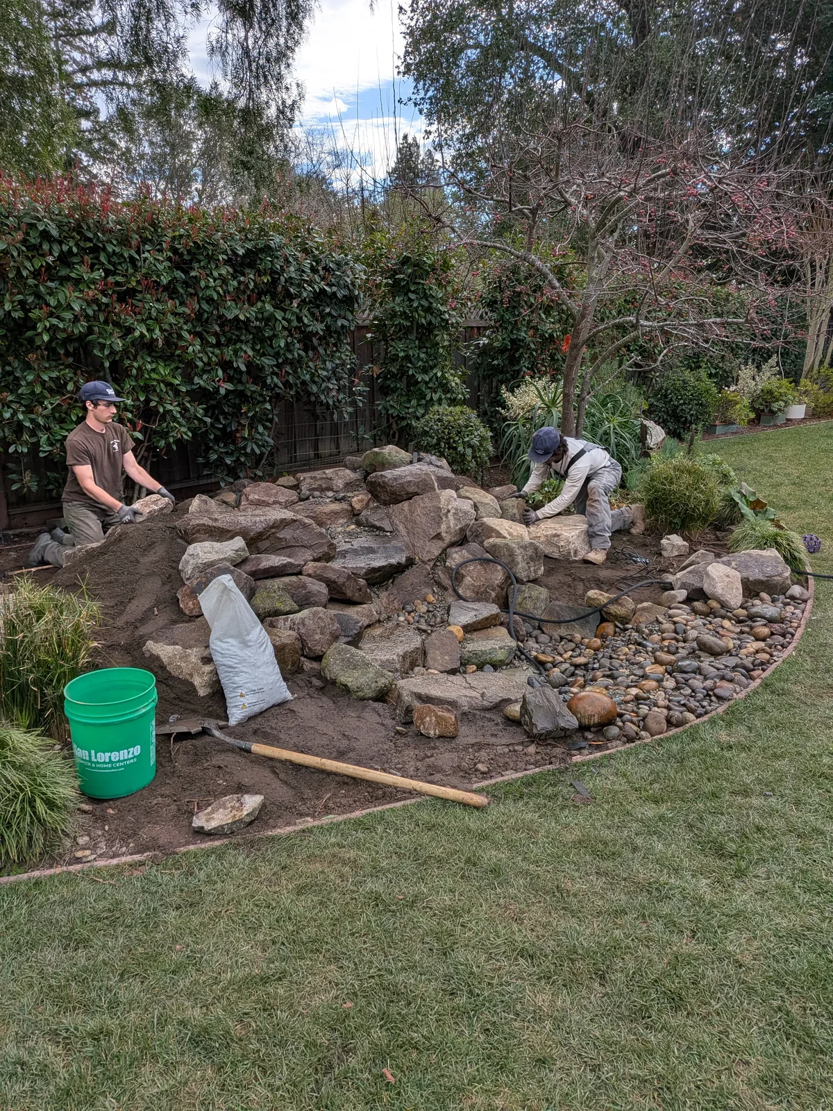 Two Water & Stone builders setting stone beside a cascading waterfall